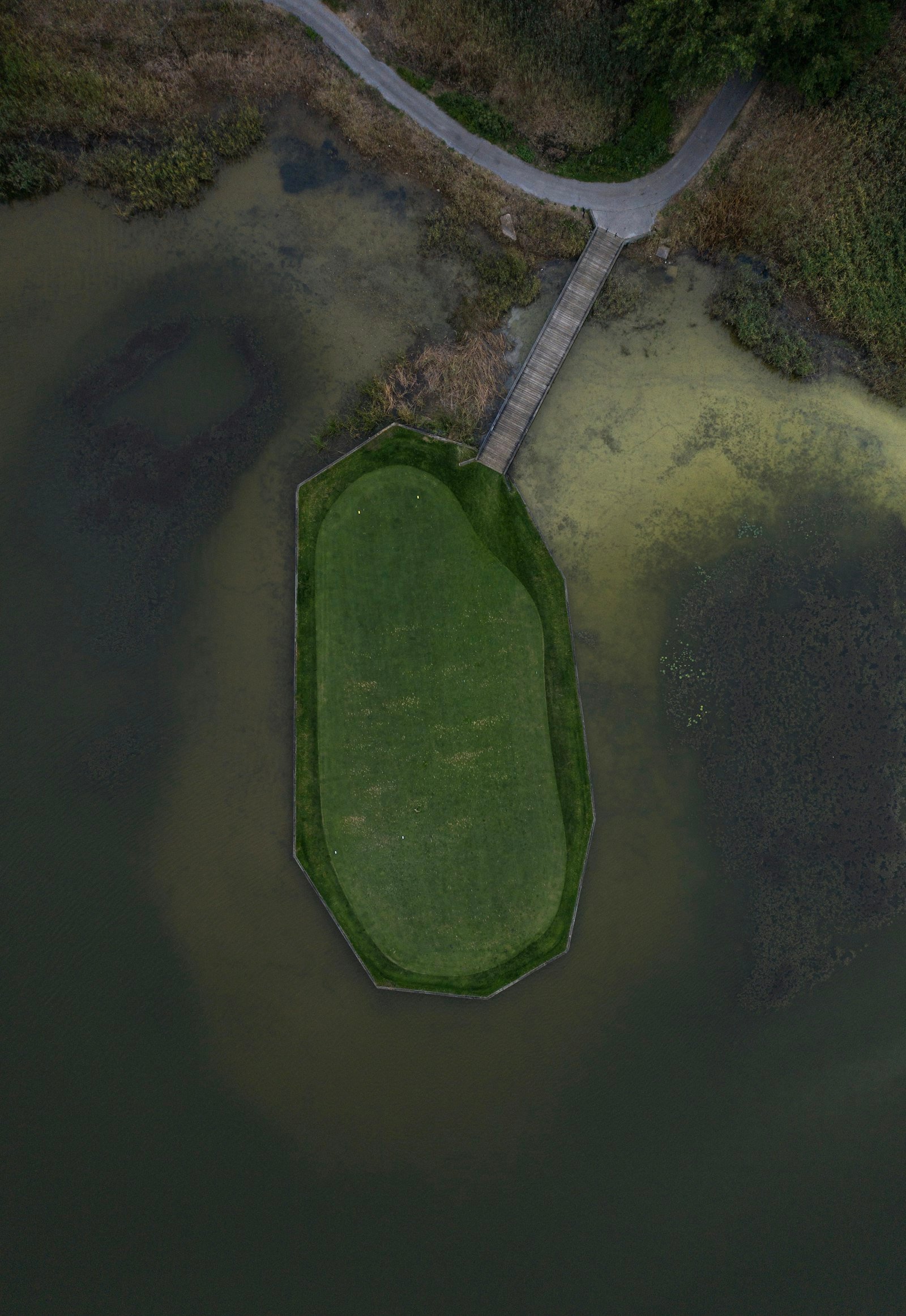 An aerial view of a golf course laid out beside open water.