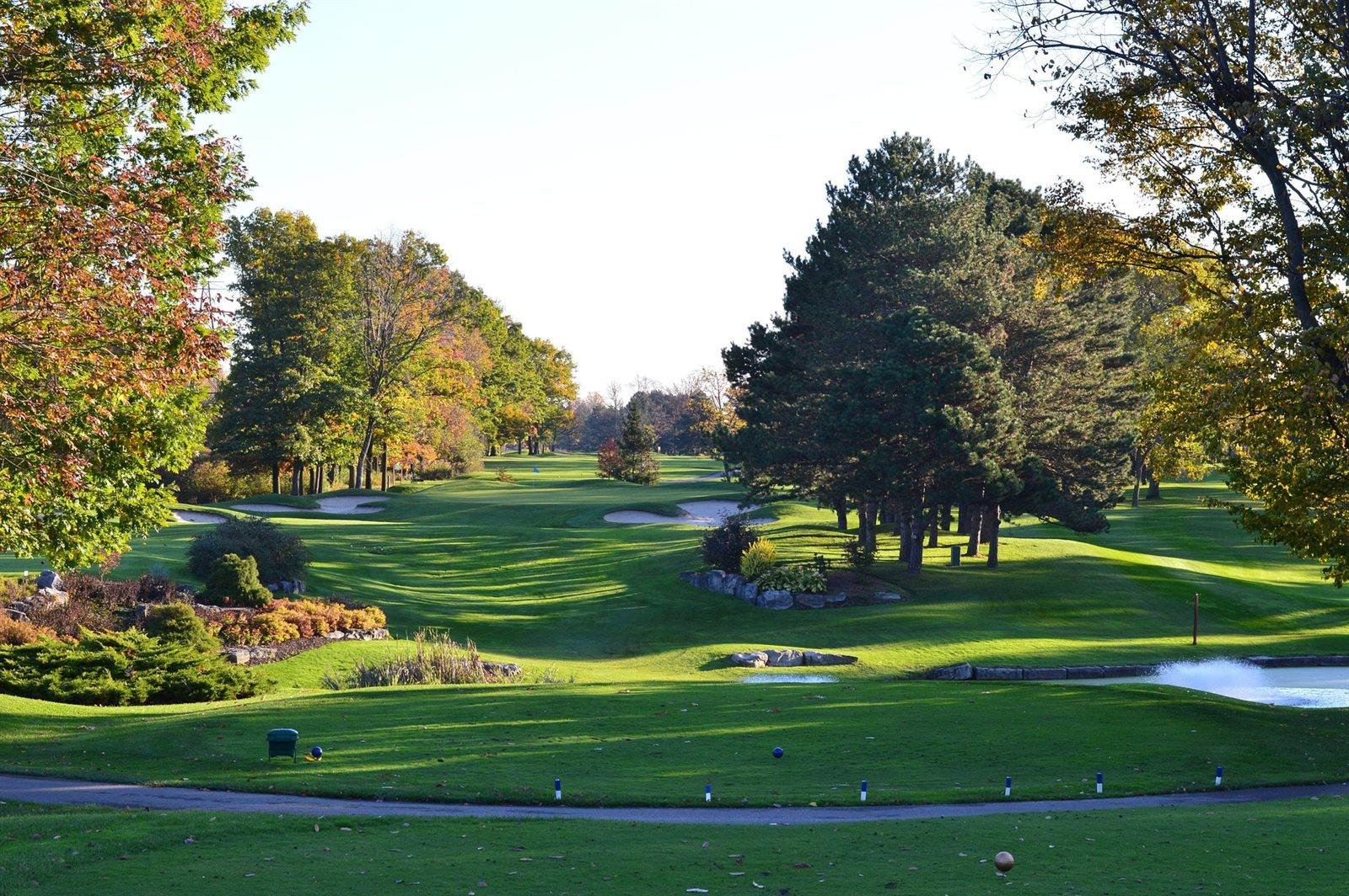 A parkland golf course in autumn colour, the fairway running away between the trees.