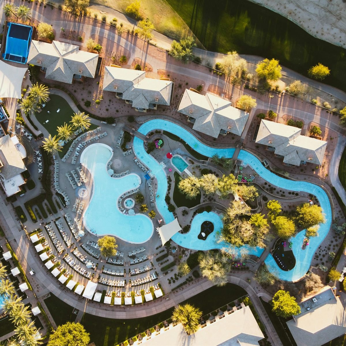 A resort lazy river winding between palms and loungers, seen from above.