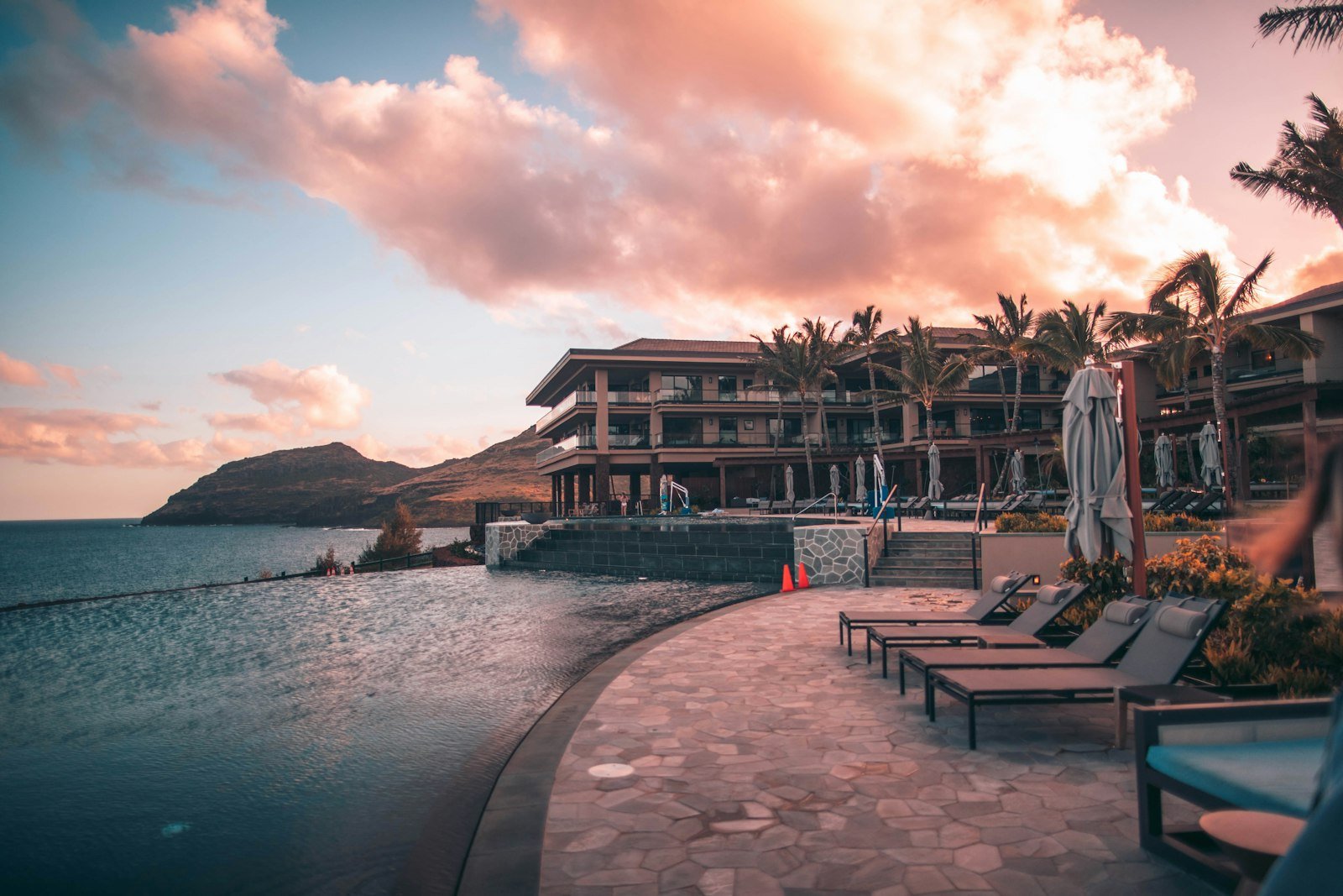 An infinity pool on a resort terrace at golden hour.