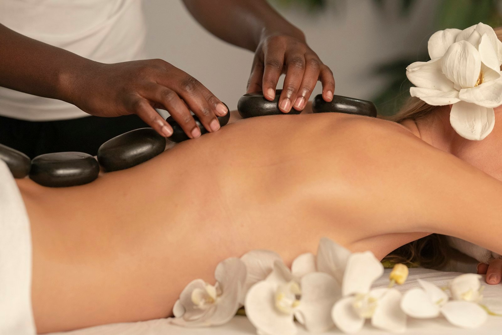 A spa treatment table set with hot stones and white flowers.